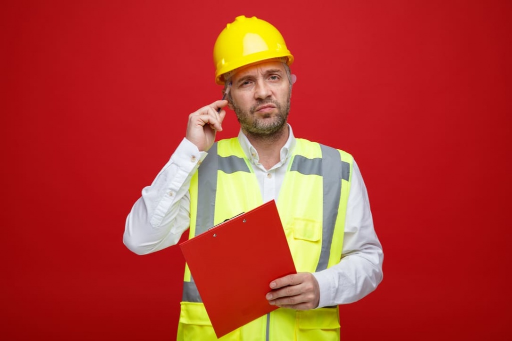 builder-man-construction-uniform-safety-helmet-holding-clipboard-looking-camera-puzzled-scratching-his-head-standing-red-background (1) (1) (1).jpg